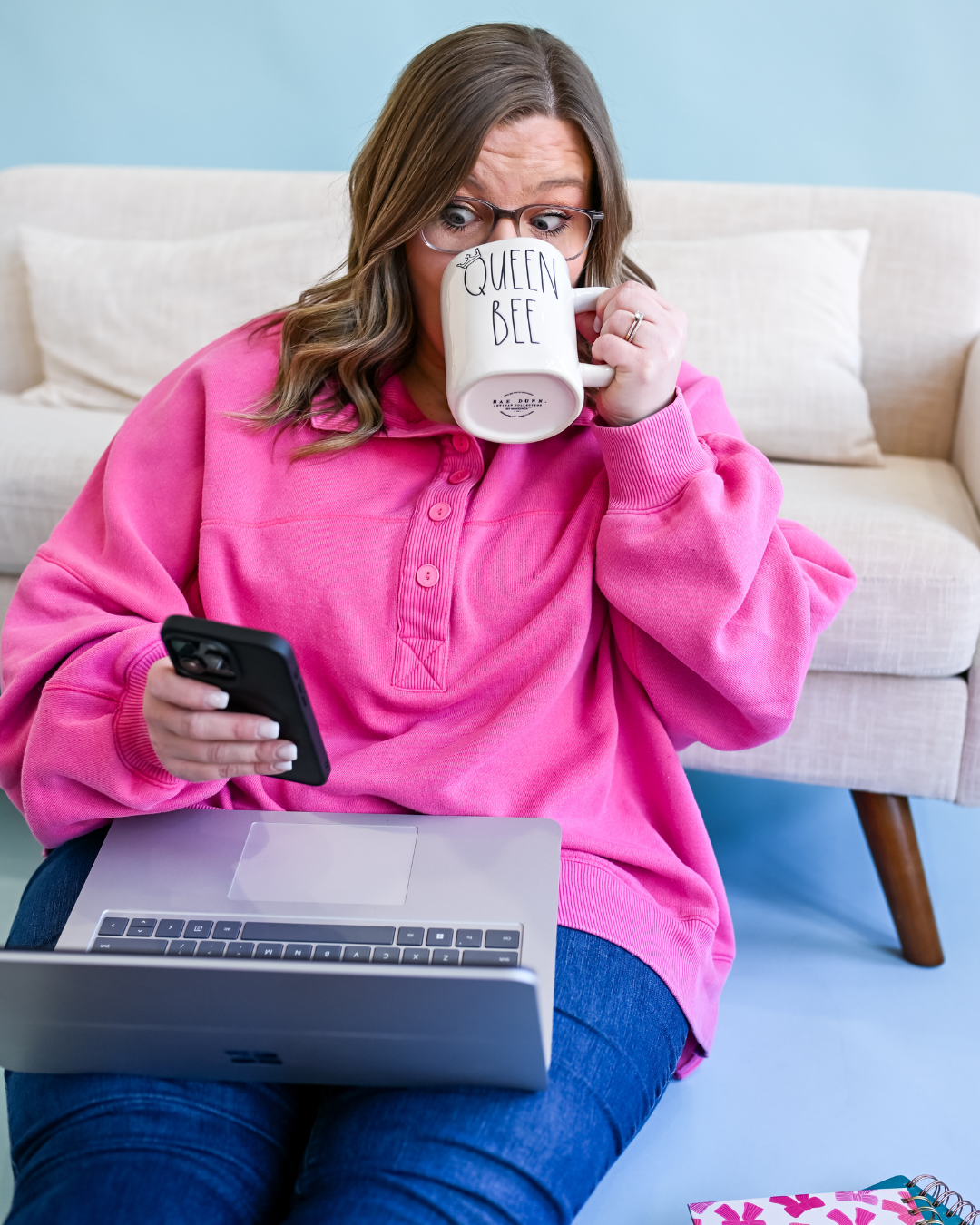 Shelb checking her phone with a Queen Bee mug
